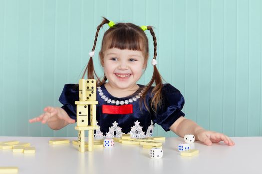 Little happy girl is playing with toys while sitting at the table