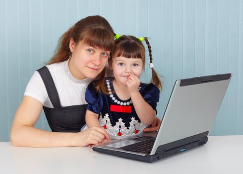 Mother and daughter sitting at the table with a computer