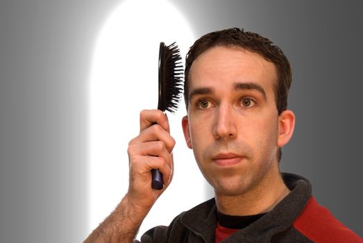 Young male brushing his hair in front of a window