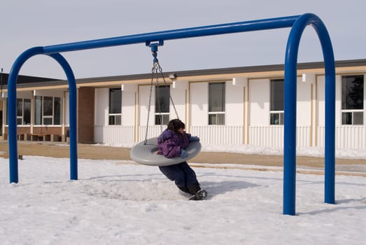 Female child on a schools tire swing