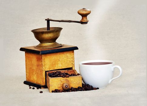 Antique coffee grinder with coffee beans an cup of hot black coffee 