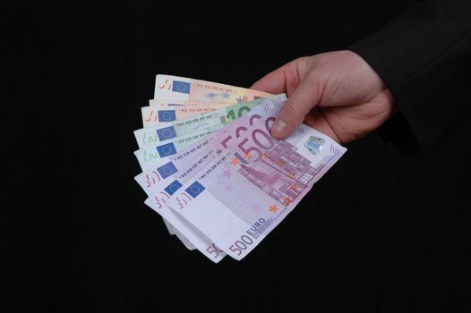 Euro in a mans hand isolated on black background