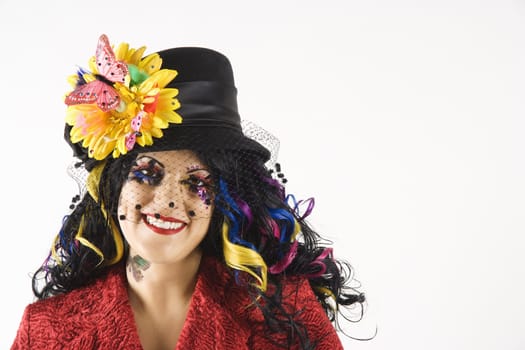 Caucasian woman in unique makeup and clothing standing against white background.