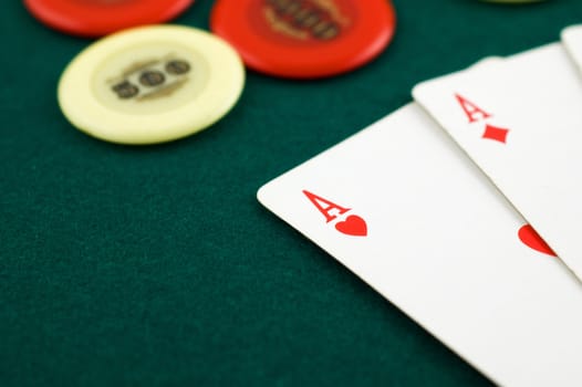 Aces and chips on green carpet with shallow depth of field