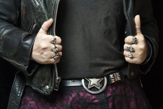 Caucasian woman's hands with silver rings holding onto black leather jacket.