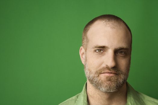 Head shot of Caucasian man with beard and receding hairline against green background.