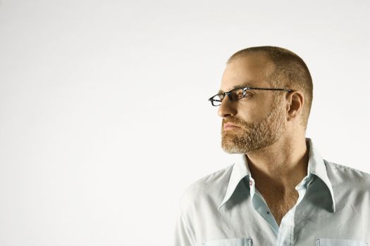 Head and shoulder portrait of Caucasian man looking to side against white background.