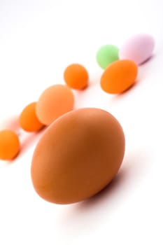 Egg in foreground with colored Easter eggs in background isolated on white