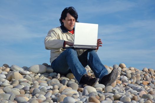 young casual man with laptop at the beach