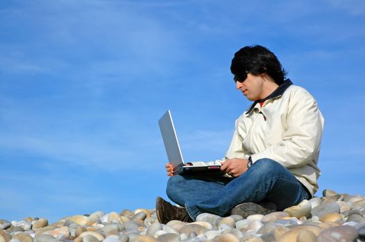 young casual man with laptop at the beach