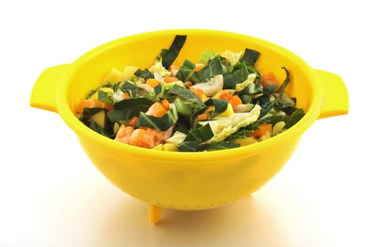 Chopped vegetables in yellow plastic bowl isolated on white