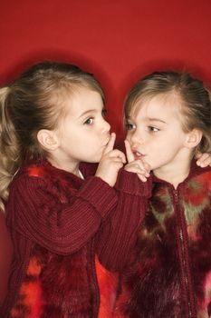 Female children Caucasian twins with fingers up to lips.