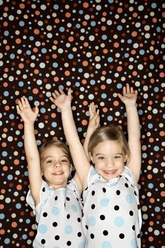 Female children Caucasian twins looking at viewer with arms raised.