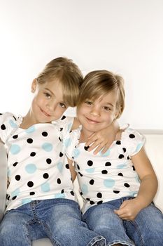 Female children Caucasian twins sitting together on chair.