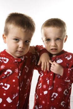 Caucasian male twin children leaning on eachother.