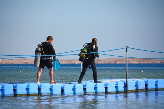 Egypt. Two men with scuba diving are on the pontoon for diving in the sea.