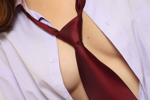 Red tie on the bared female breast removed close up
