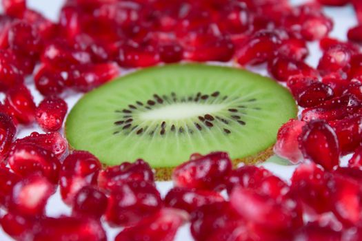 The cut fruit kiwi against garnet grains removed close up