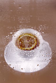 Cup of tea with a lemon behind glass splashed with water drops