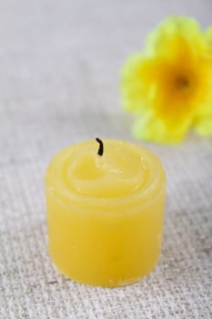 Extinct candle on a linen napkin removed close up against a yellow flower