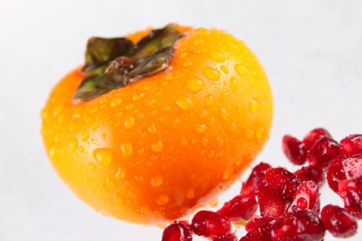 Pomegranate and a persimmon removed close up on a white background without isolation