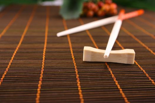 Chopsticks on a bamboo napkin removed close up against green foliage