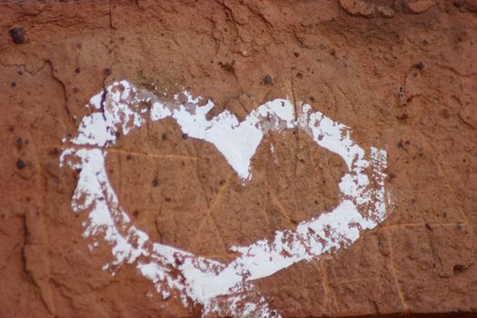 Heart symbol drawn by a white paint on a red brick