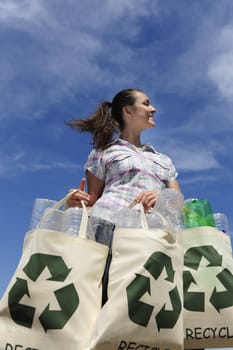 recycling: woman holding bag with plastic bottles against blue sky