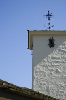 old white stucco tower with metal weather vane