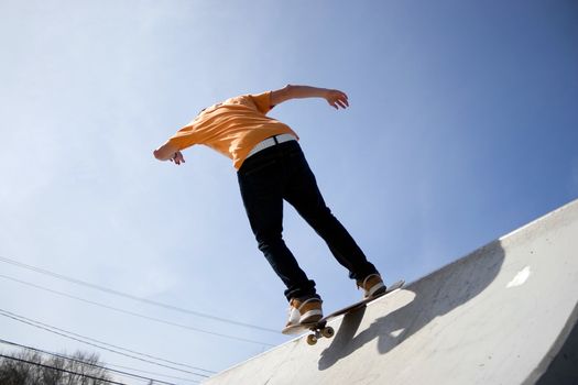 Action shot of a teenage skateboarder skating down a ramp at the skate park.