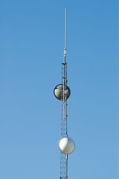 A tall tower with satellites in order to receive signals, shot against a blue sky