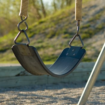 A single swing, sitting empty on a playground