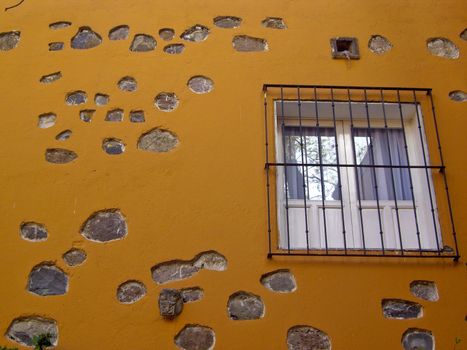 Barred window on color stone wall