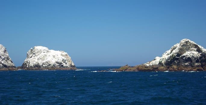 Some of the smaller Farallon Islands covered in white bird guano.