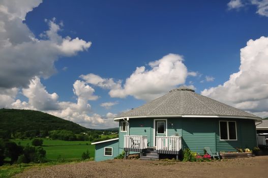 A sixteen-sided house perched on a hillside overlooking a lush green river valley.