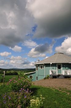 A sixteen-sided house perched on a hillside overlooking a lush green river valley.