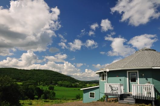 A sixteen-sided house perched on a hillside overlooking a lush green river valley.