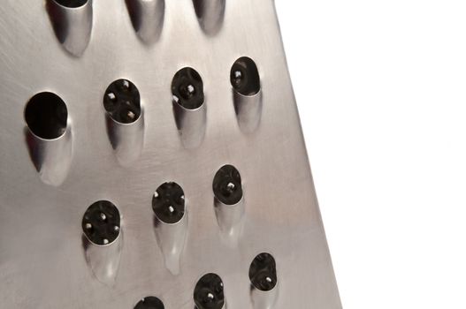 Close up and low level capturing a portion of a steel cheese grater arranged in the left of the image with white background.