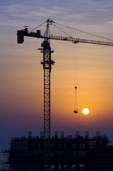 Tower crane on a construction site at sunrise