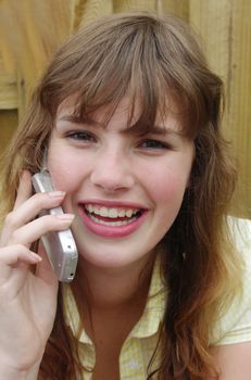 Beautiful blond teenage girl laughing into cellphone.
