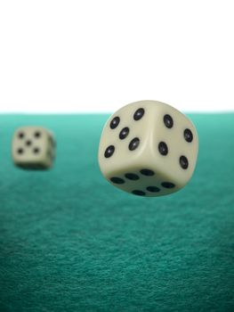 A pair of dices rolling over a green felt.