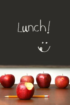 Apples on top of school desk with chalkboard in background