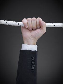 Close up on a businessman's hand hanging on a rope.