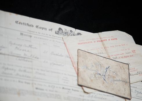 Old family certificates and In Memoriam card being used to research family tree.