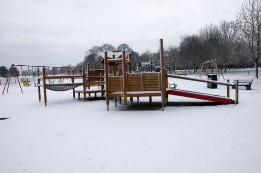 A childrens park in the snow with a jungle-gym