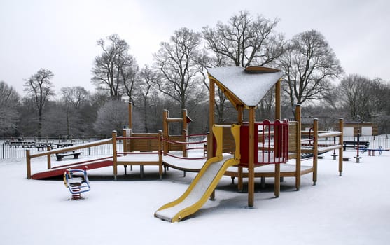 A childrens park in the snow with a jungle-gym