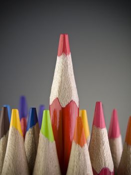 Red pencil coming out among many colored pencils.