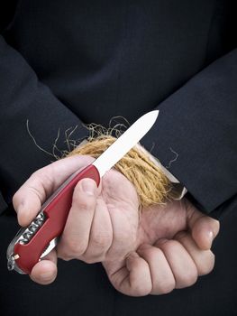 Closeup on a businessman's hands trying to set himself free.