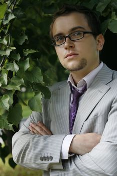 Portrait of the young serious businessman on a background of a tree