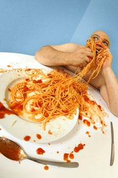 An overweight man enjoying a plate of spaghetti.  Shot with fish-eye lens.  Focus is on the face.
